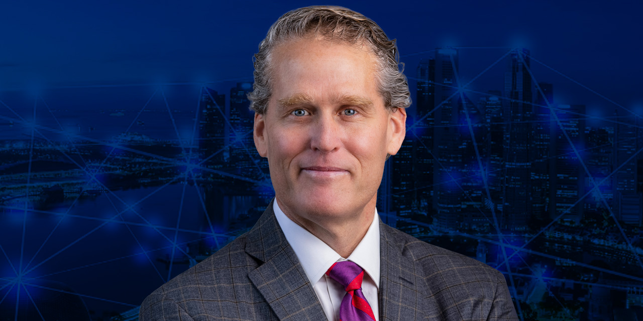 Headshot of John Langenfeld with an abstract blue background.