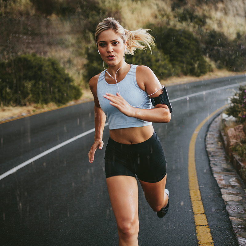 Woman running on a rural road wearing headphones.