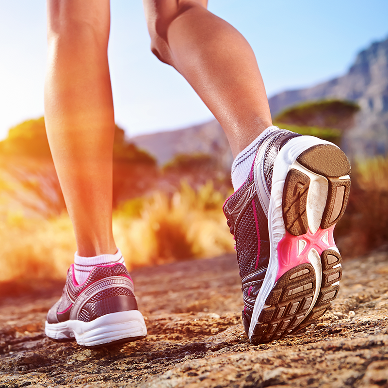 Closeup image of feed wearing tennis shoes on a hiking path.