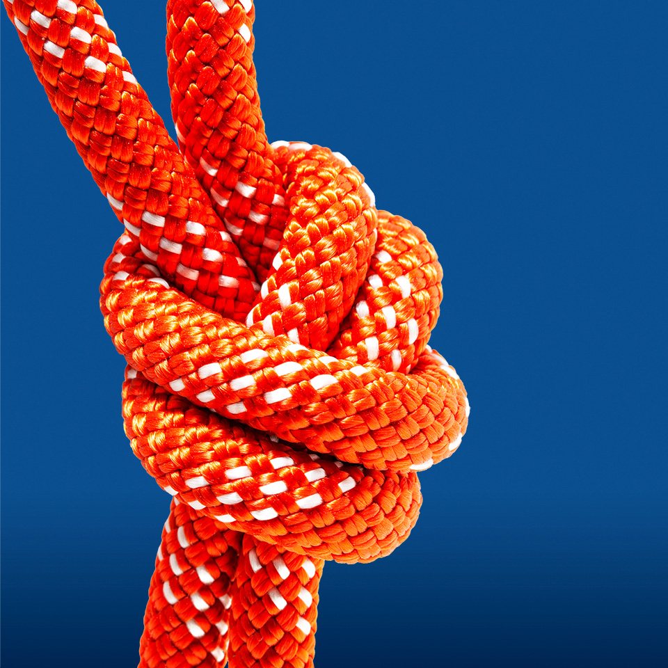 Closeup of a knot tied in red rope on a blue background
