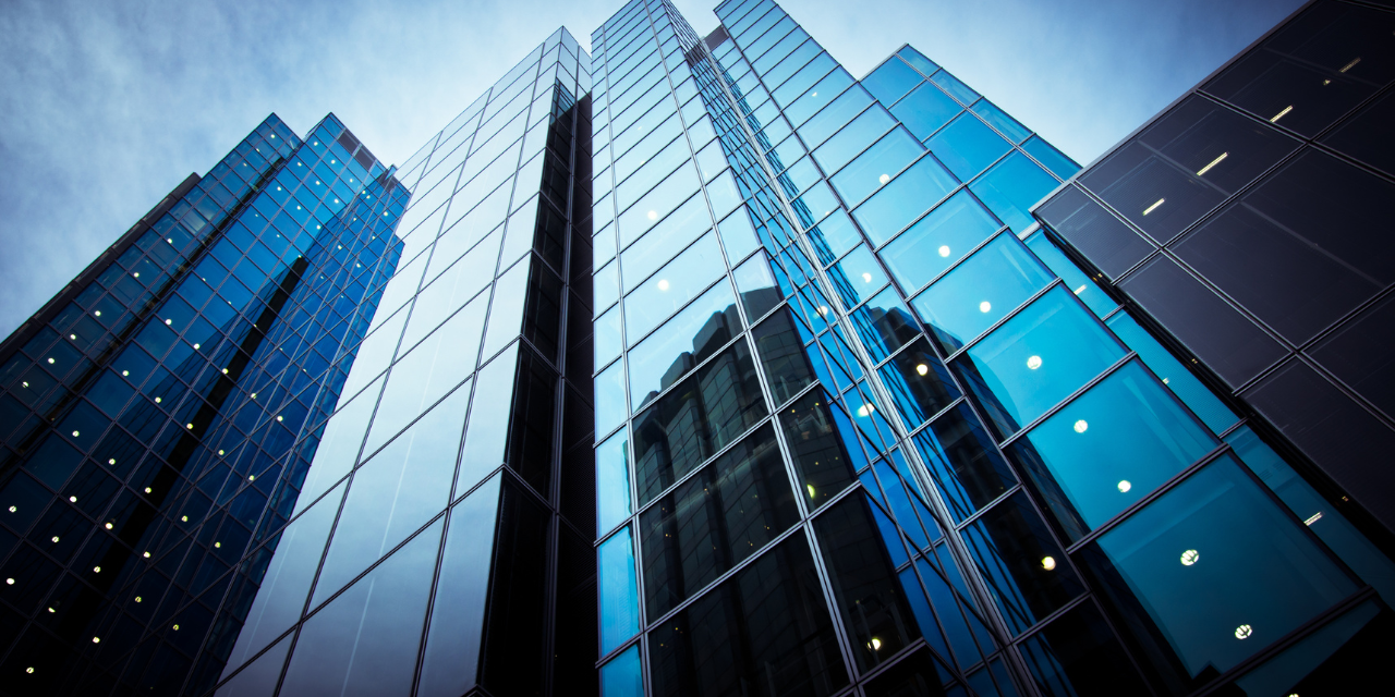 Photo from the grown looking up at skyscrapers with reflective windows.