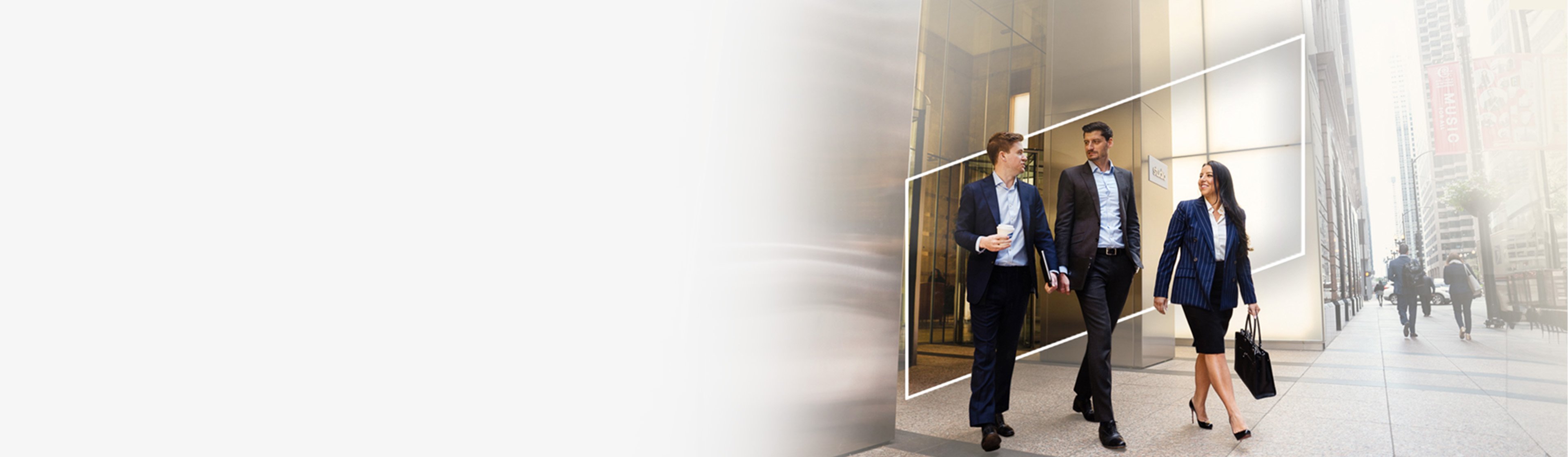 three Baird associates walking out of a city office building framed by the Baird logo