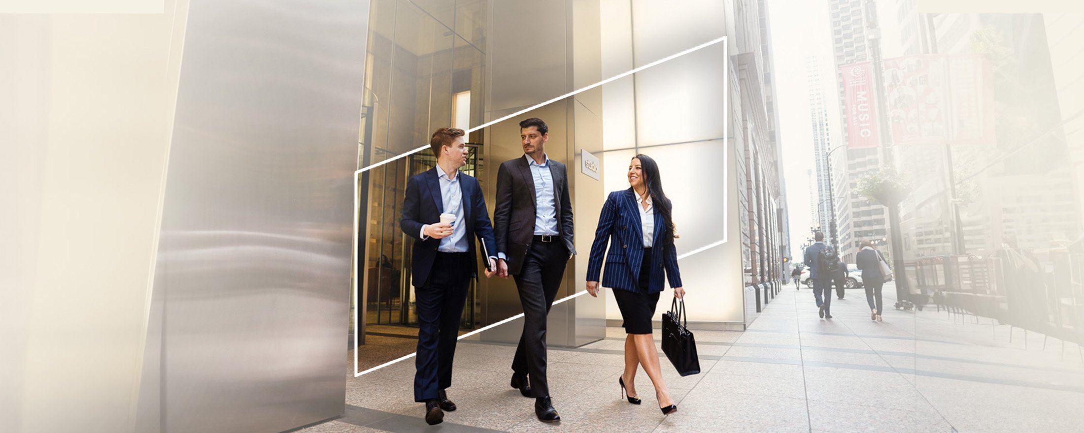 three Baird associates walking out of a city office building framed by the Baird logo