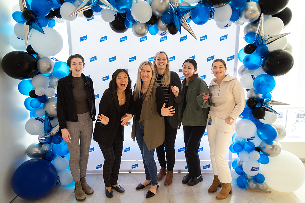 Group of Baird Associates standing as a group under a balloon arch.