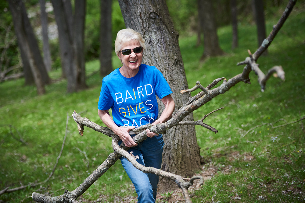 Baird leadership team member carrying tree branches while volunteering.