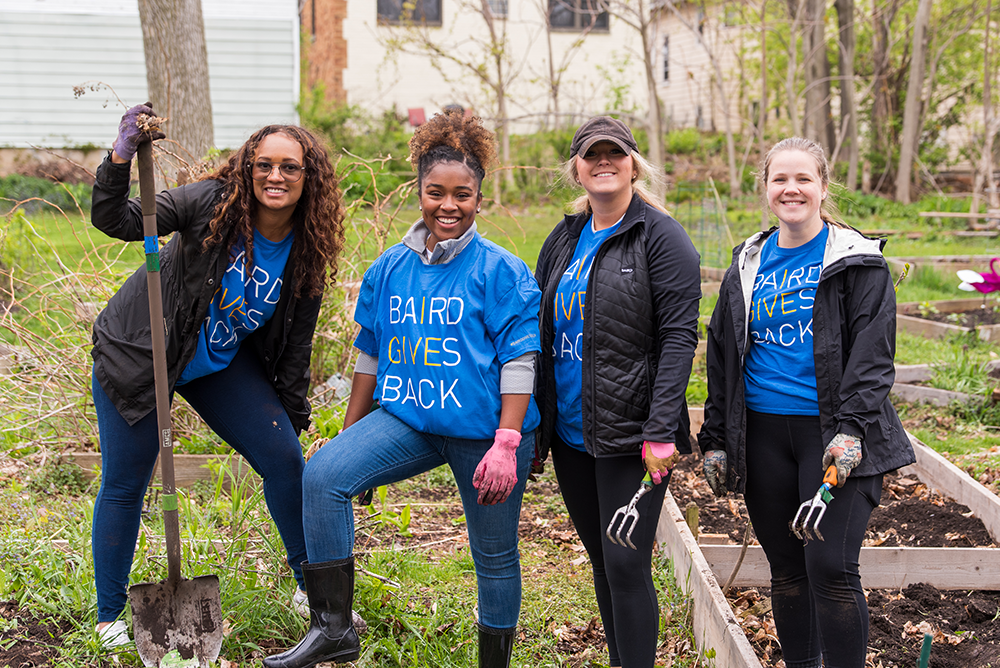 Four Baird associates working in an outdoor garden while volunteering.