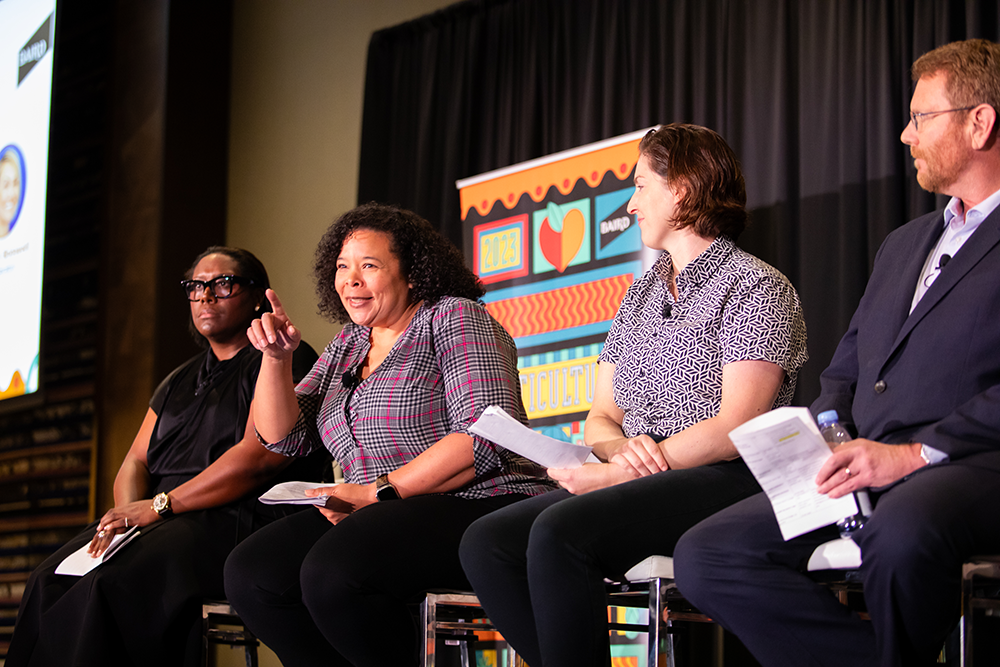 Panelists on stage sitting on chairs.