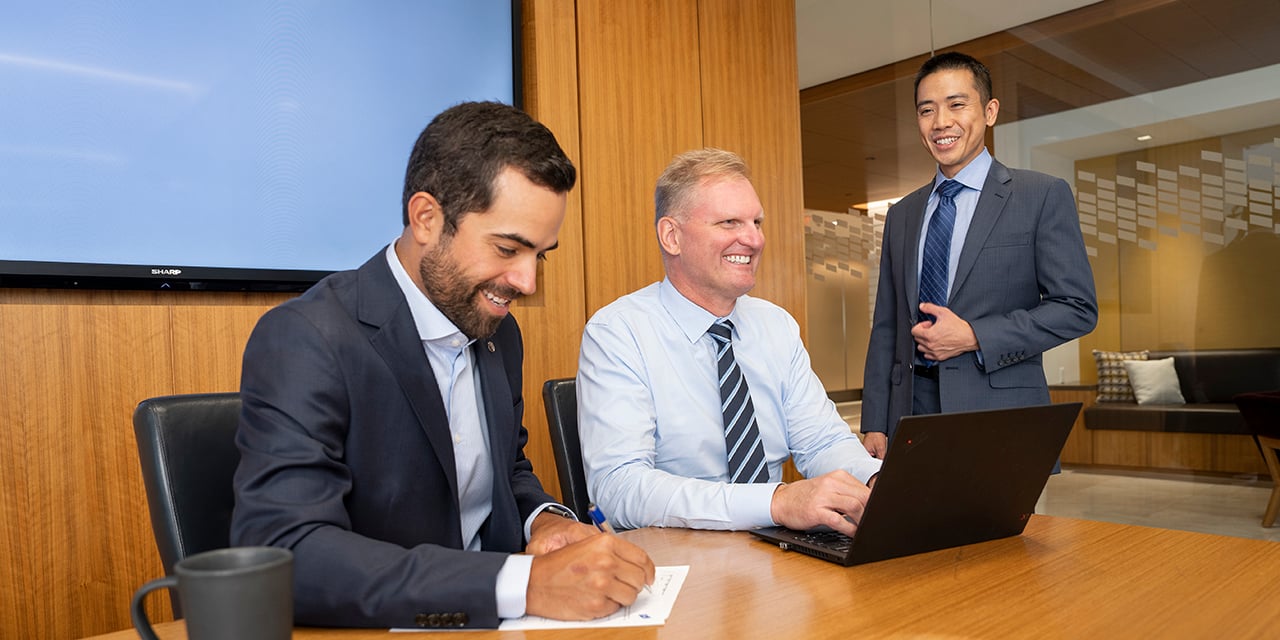 Business professionals at a conference room table with a laptop.