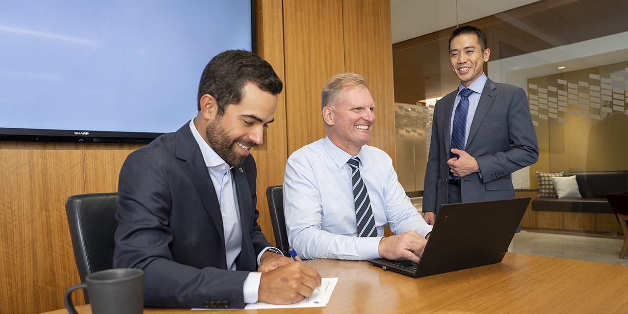 Business professionals at a conference room table with a laptop.