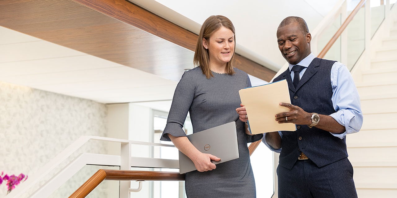 Two professionals looking at paperwork while standing on a staircase