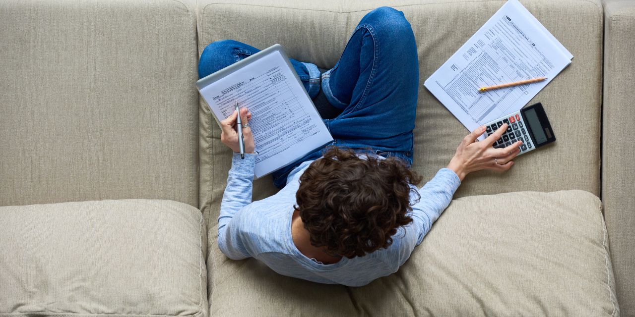 Overhead photo of a person working on tax paperwork on their sofa