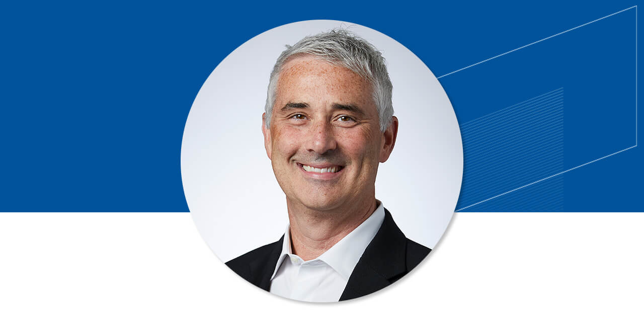 Headshot of Michael Antonelli on a blue background with an abstract Baird logo