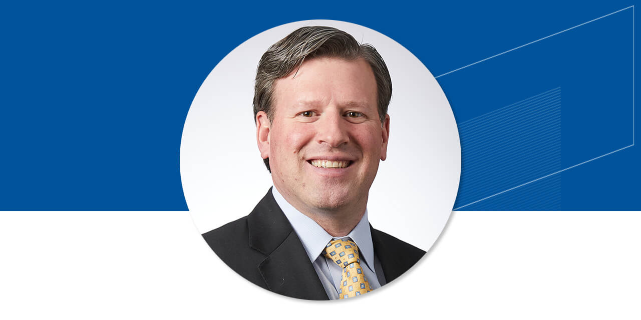 Headshot of Scott Grenier on a blue background with an abstract Baird logo