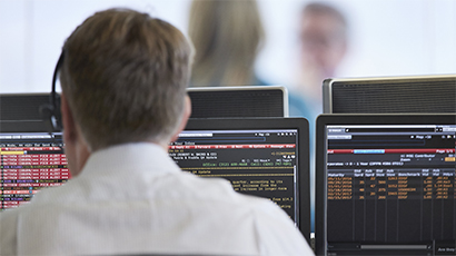 Man sitting at computer looking at monitors on the Baird trading floor.