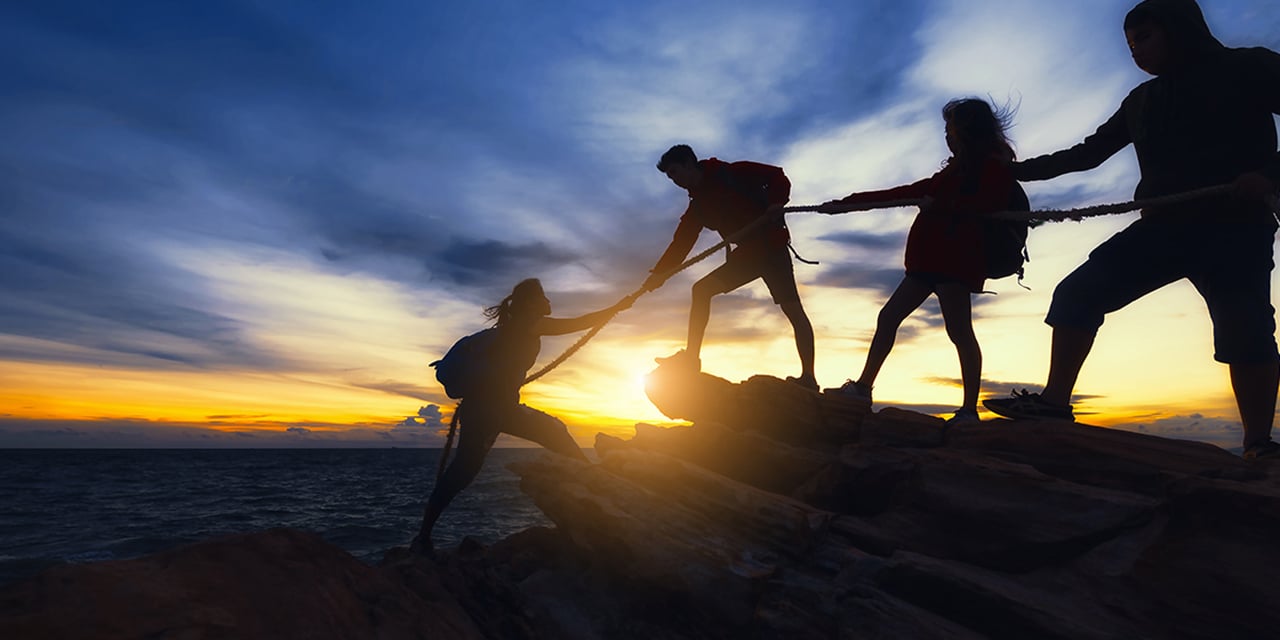 Four people hiking on a bluff at sunset.