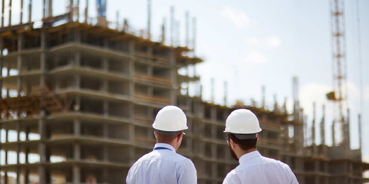 Two people in hard hats looking at construction site.